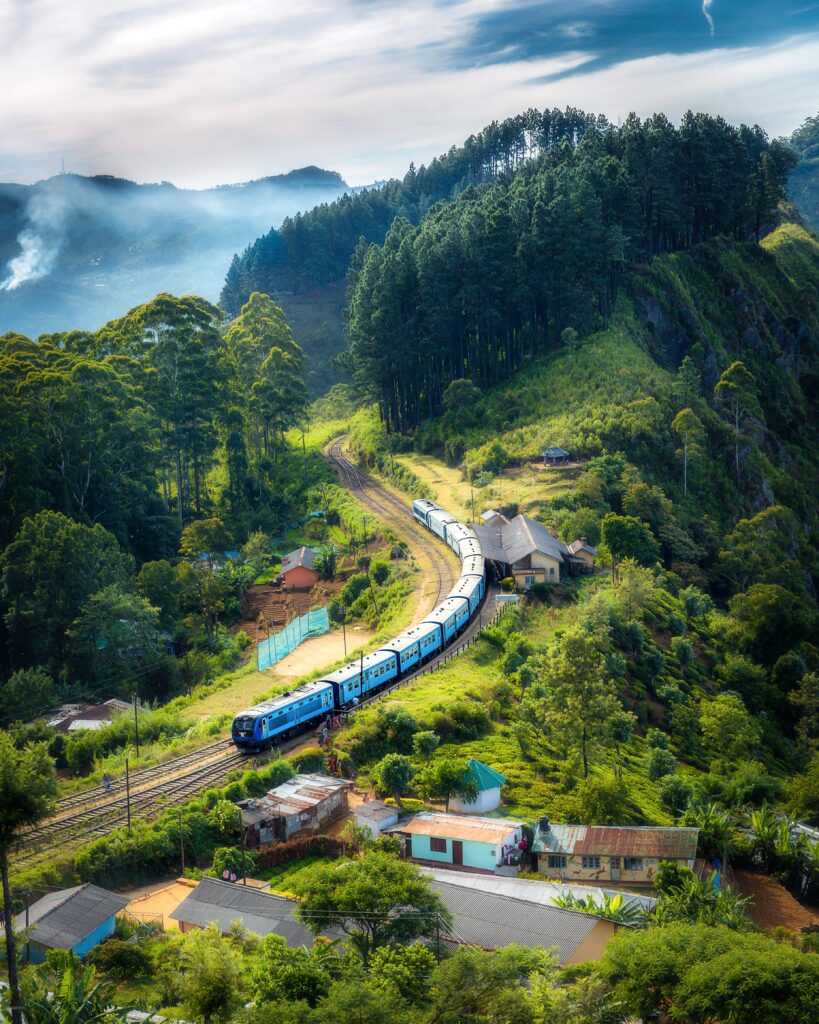 Aerial view of a picturesque train winding through lush green hills and rural houses.